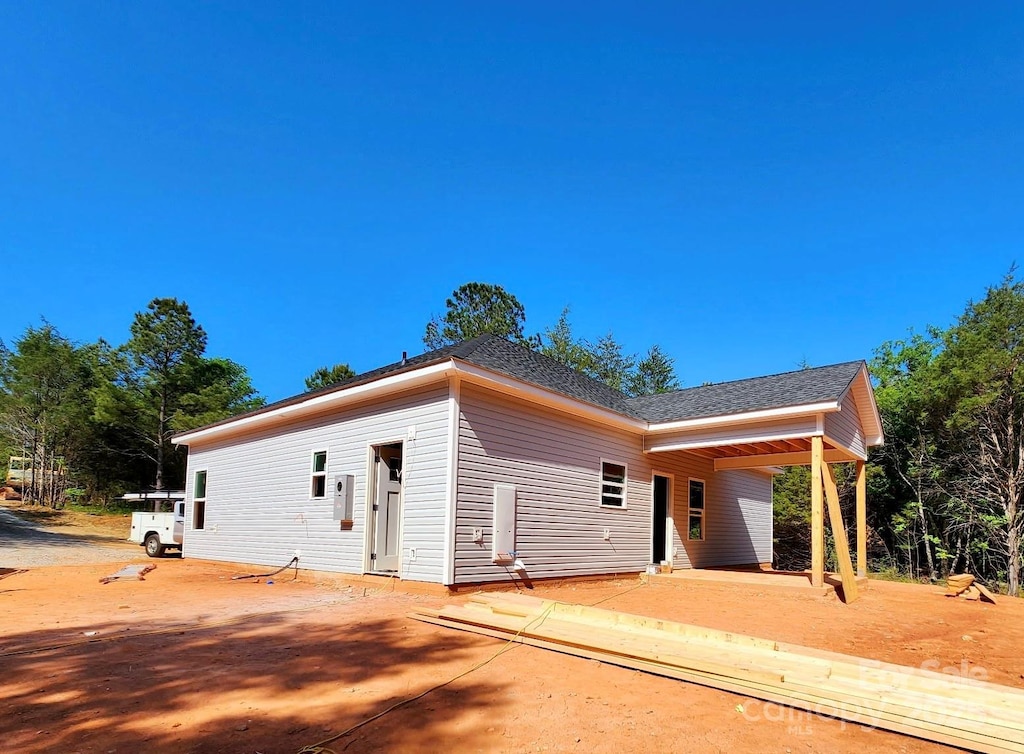 rear view of property featuring a shingled roof