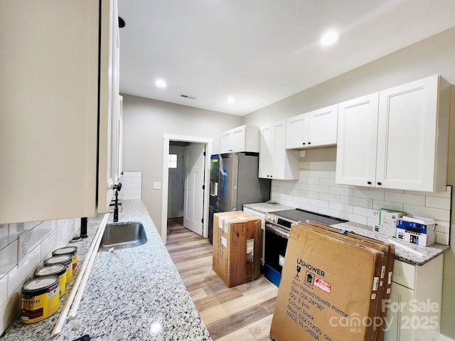 1247 Beltline Rd Unit 1, Chester, SC 29706 - kitchen with appliances with stainless steel finishes, white cabinetry, light stone counters, light wood-style flooring, and backsplash