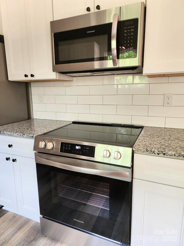 1247 Beltline Rd Unit 1, Chester, SC 29706 - kitchen featuring appliances with stainless steel finishes, white cabinets, light stone countertops, tasteful backsplash, and wood finished floors