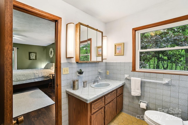 675 Terrys Gap Rd, Hendersonville, NC 28792 - ensuite bathroom with tile walls, vanity, toilet, ceiling fan, and wainscoting