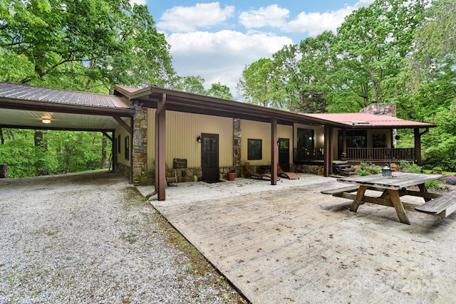 675 Terrys Gap Rd, Hendersonville, NC 28792 - rear view of house featuring stone siding, driveway, an attached carport, a chimney, and metal roof