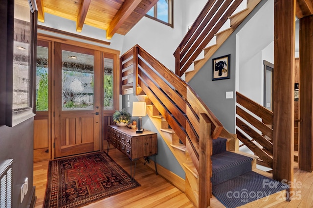 entrance foyer with light wood-type flooring, lofted ceiling with beams, and stairway