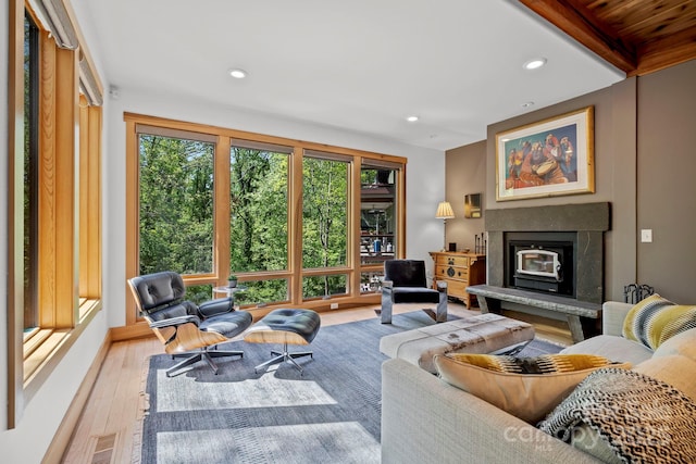 living room with a glass covered fireplace, recessed lighting, wood finished floors, and visible vents