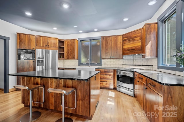 kitchen with light wood-style floors, open shelves, stainless steel appliances, and brown cabinets