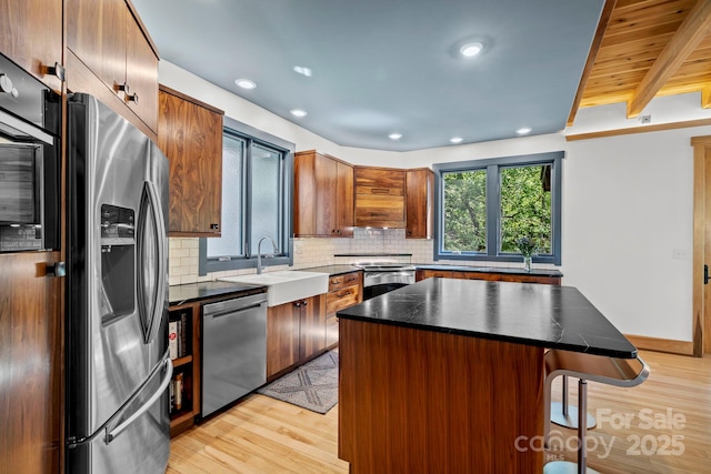 kitchen with a breakfast bar area, stainless steel appliances, a sink, and light wood-style floors