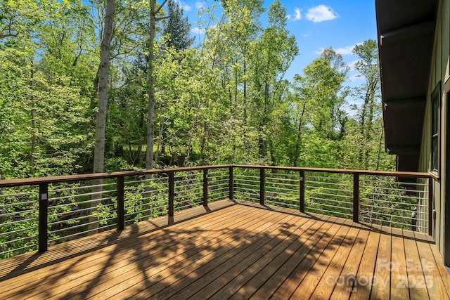 wooden terrace featuring a view of trees