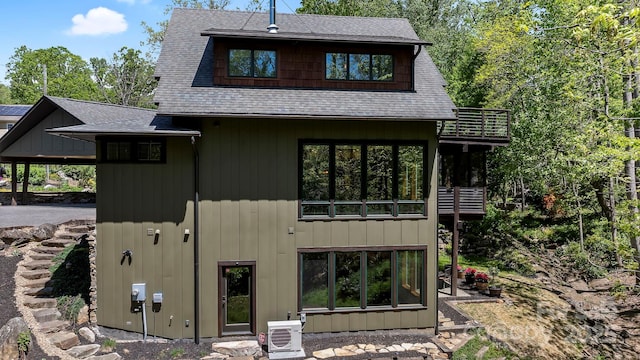 back of property with a shingled roof and ac unit