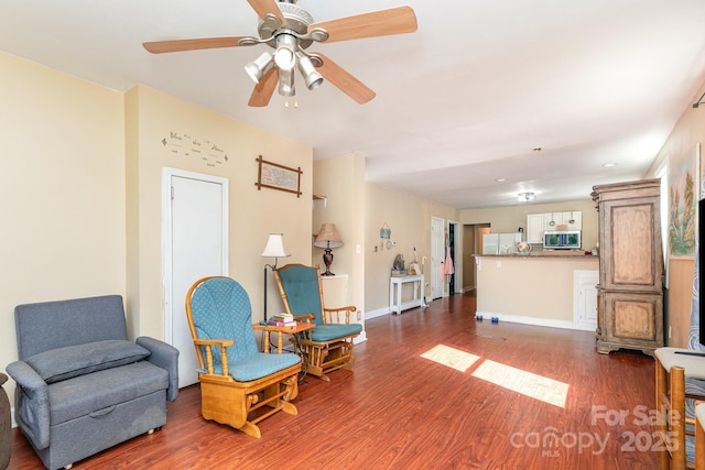 sitting room featuring wood finished floors, a ceiling fan, and baseboards