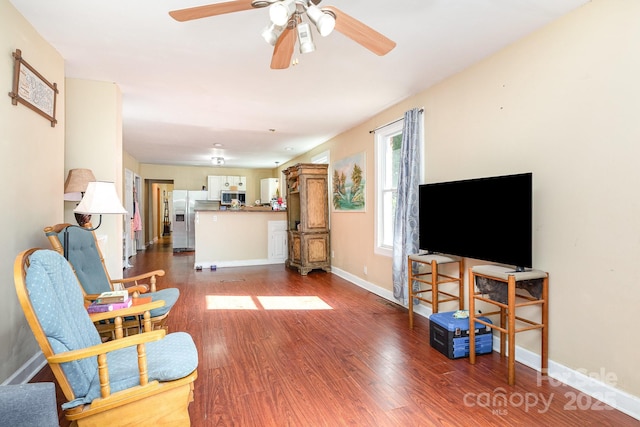living area featuring ceiling fan, baseboards, and wood finished floors