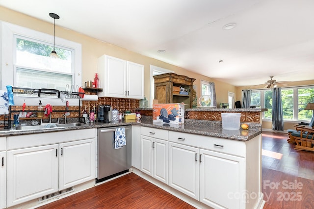 kitchen featuring stainless steel dishwasher, visible vents, a sink, a peninsula, and dark wood-style floors