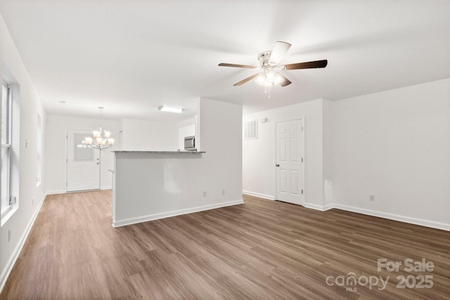 7616 Monarch Birch Ln, Charlotte, NC 28215 - unfurnished living room featuring visible vents, baseboards, ceiling fan with notable chandelier, and wood finished floors