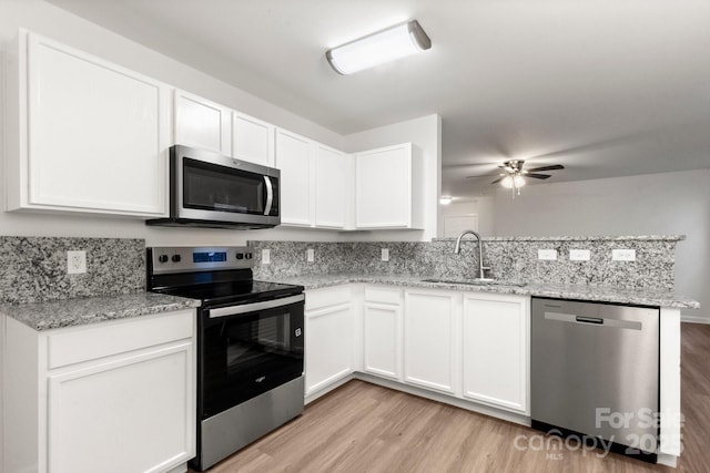 7616 Monarch Birch Ln, Charlotte, NC 28215 - kitchen with a sink, a peninsula, stainless steel appliances, and light wood finished floors
