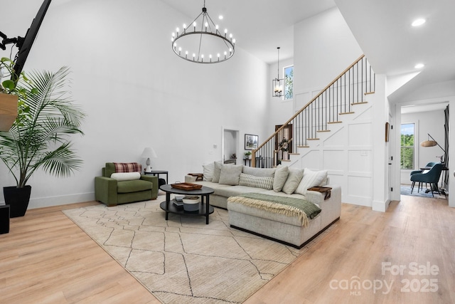 living room featuring wood finished floors, a chandelier, stairs, a towering ceiling, and plenty of natural light