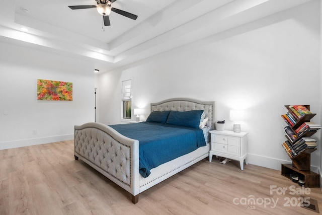 bedroom featuring light wood finished floors, a tray ceiling, baseboards, recessed lighting, and ceiling fan