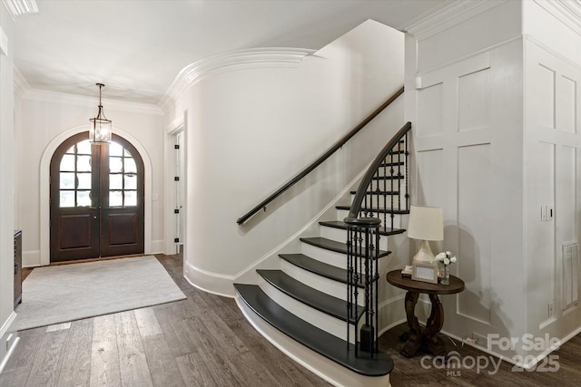 entryway featuring arched walkways, baseboards, stairway, and wood finished floors