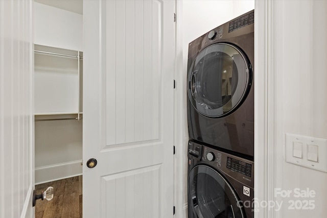 laundry area featuring laundry area, stacked washer and dryer, and wood finished floors