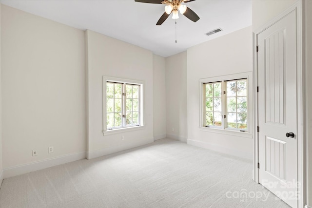 spare room with plenty of natural light, light carpet, a ceiling fan, and visible vents