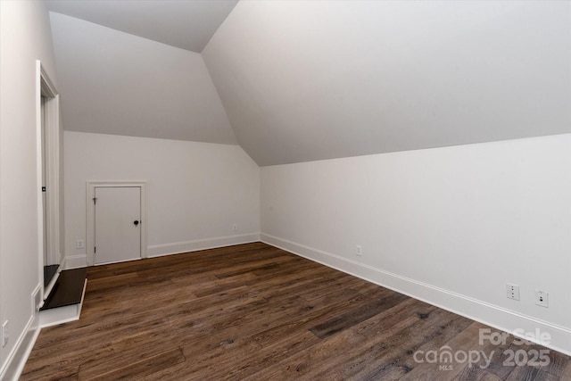 bonus room with dark wood finished floors, vaulted ceiling, and baseboards