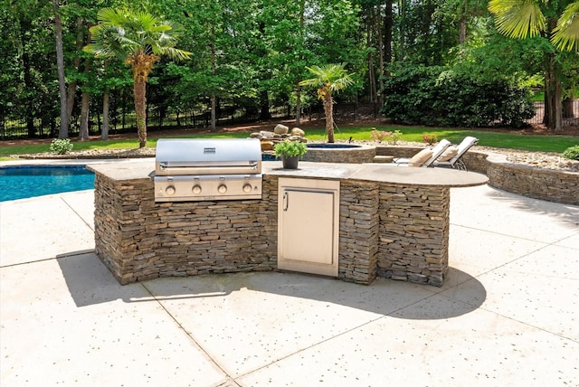 view of patio featuring area for grilling, an outdoor pool, and exterior kitchen