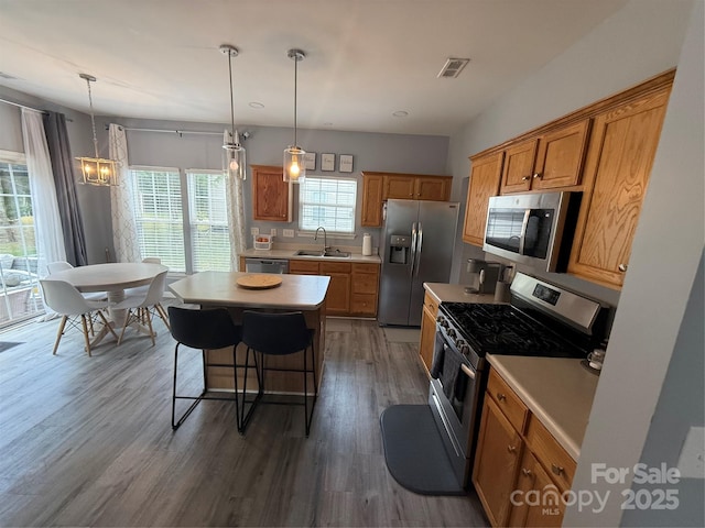 12244 Wallace Ridge Dr, Charlotte, NC 28269 - kitchen with appliances with stainless steel finishes, a breakfast bar, a sink, light countertops, and visible vents