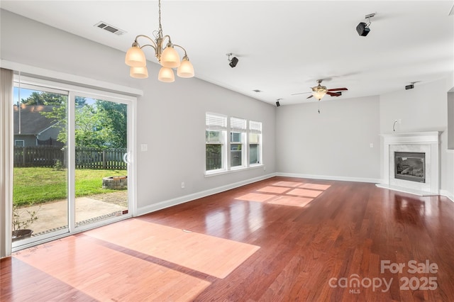 unfurnished living room with a fireplace, ceiling fan with notable chandelier, baseboards, wood finished floors, and visible vents