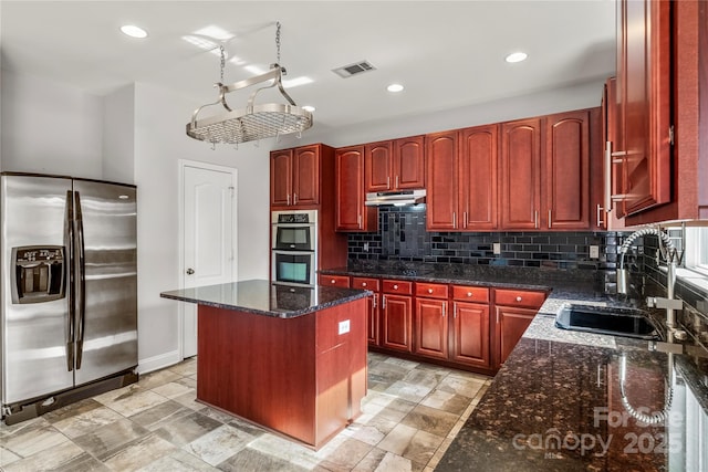 kitchen with dark brown cabinets, a sink, stainless steel appliances, tasteful backsplash, and visible vents