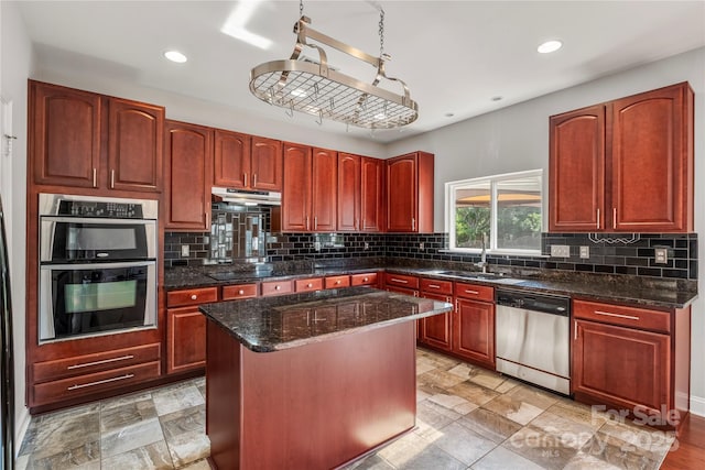 kitchen with a sink, stainless steel appliances, tasteful backsplash, a kitchen island, and under cabinet range hood