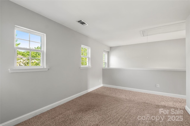 spare room featuring baseboards, visible vents, carpet, and attic access
