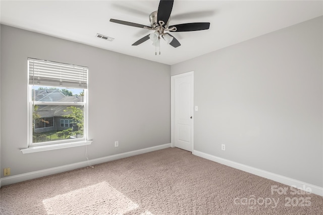 carpeted spare room with a ceiling fan, baseboards, and visible vents
