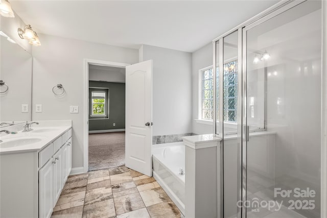 bathroom featuring a garden tub, a sink, baseboards, and double vanity