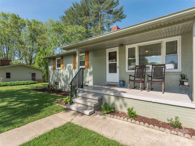 view of front facade with covered porch, brick siding, a chimney, and a front yard