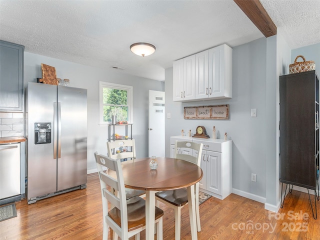 dining space featuring a textured ceiling, baseboards, and light wood-style floors