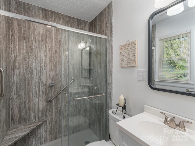 full bathroom featuring toilet, a textured ceiling, a shower stall, and vanity