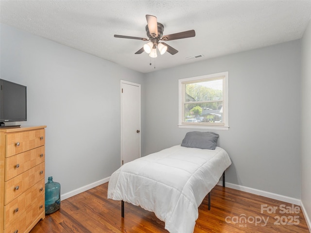 bedroom with visible vents, baseboards, and wood finished floors