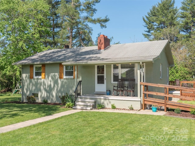 single story home featuring a front lawn, roof with shingles, covered porch, and a chimney