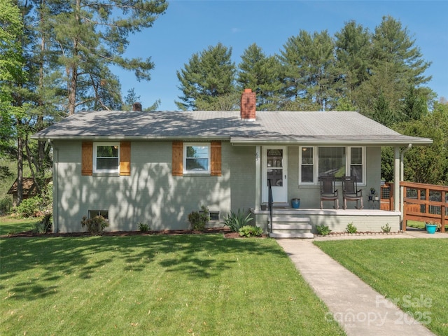 view of front of home featuring covered porch, brick siding, a chimney, and a front yard