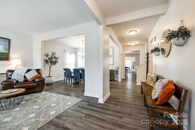 living area featuring baseboards, dark wood-style flooring, and a chandelier