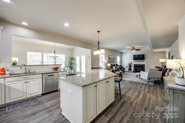 kitchen featuring dark wood-style flooring, dishwasher, a sink, white cabinets, and a glass covered fireplace