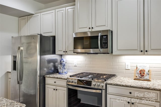 kitchen with light stone counters, backsplash, and stainless steel appliances