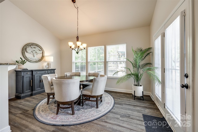 dining room featuring an inviting chandelier, baseboards, dark wood finished floors, and lofted ceiling