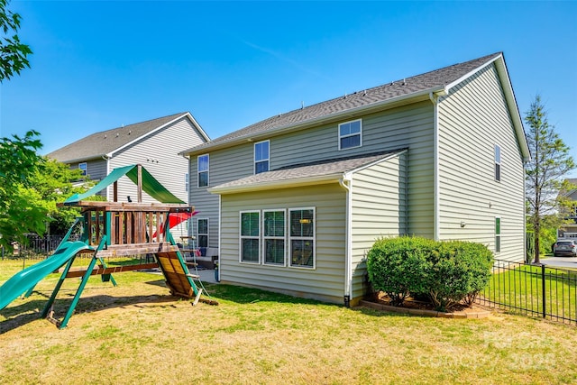 rear view of property featuring a lawn, fence, and a playground