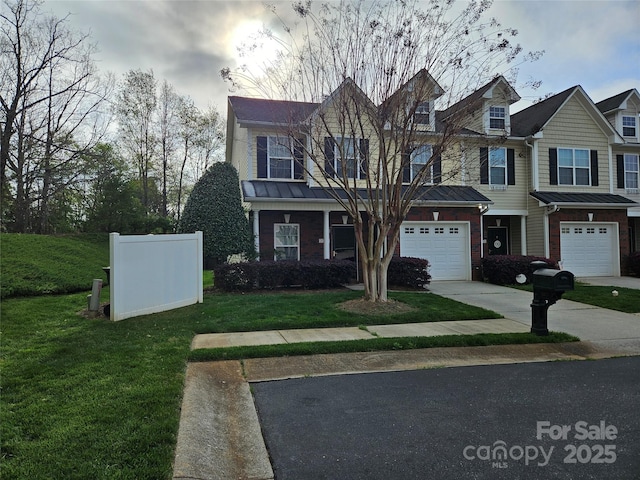 view of front of house featuring a standing seam roof, a front yard, a garage, brick siding, and concrete driveway