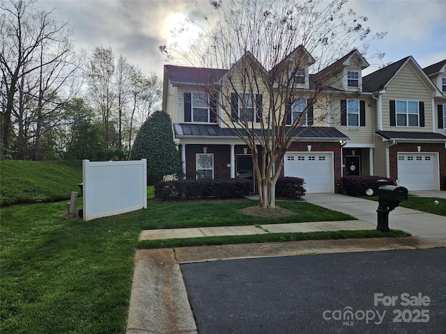 view of front of home with an attached garage, a front lawn, concrete driveway, a standing seam roof, and metal roof