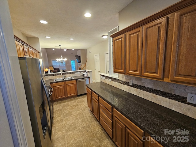 kitchen with a notable chandelier, appliances with stainless steel finishes, a sink, a peninsula, and pendant lighting