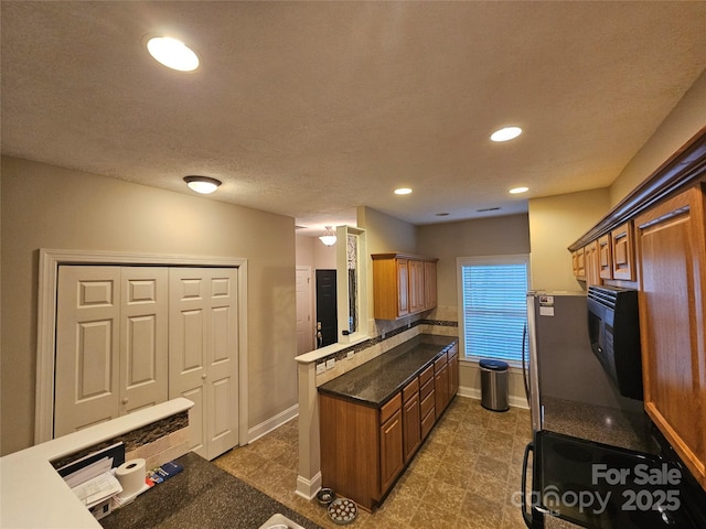 kitchen featuring baseboards, recessed lighting, a peninsula, and brown cabinets