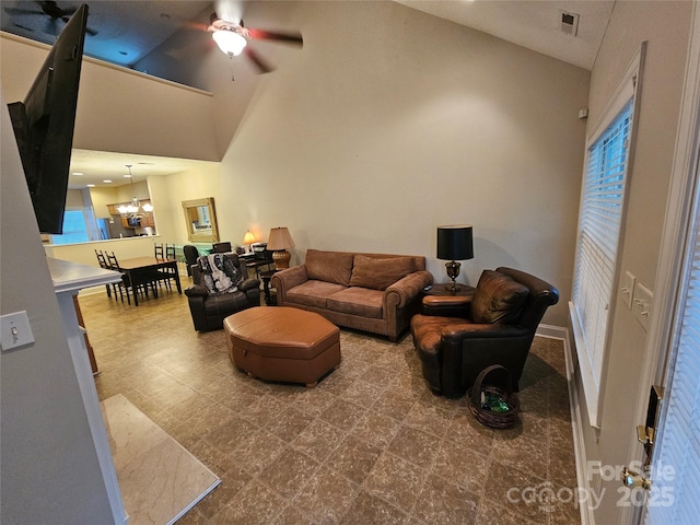 living room featuring visible vents, ceiling fan with notable chandelier, and high vaulted ceiling