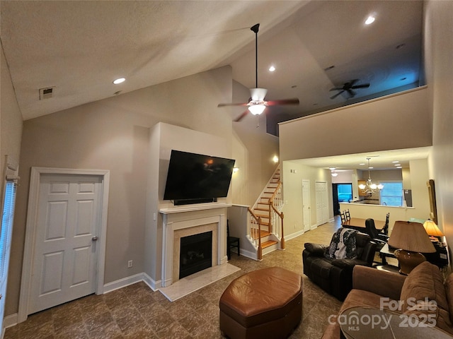 living area featuring baseboards, a fireplace with flush hearth, stairs, and high vaulted ceiling