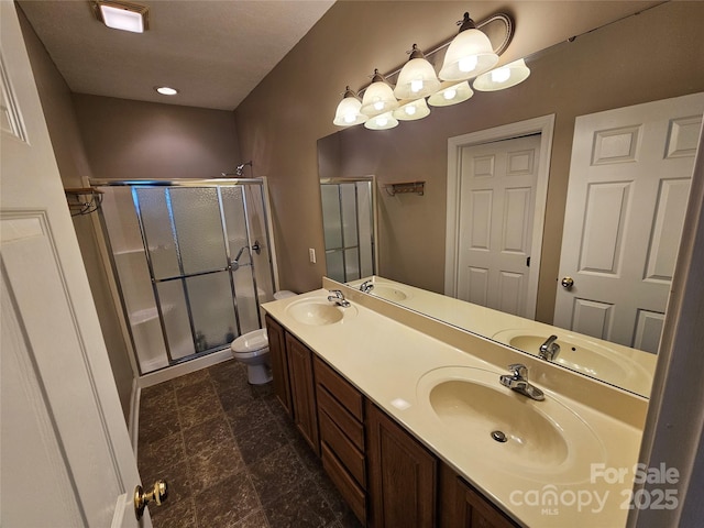 bathroom featuring double vanity, toilet, a sink, and a stall shower