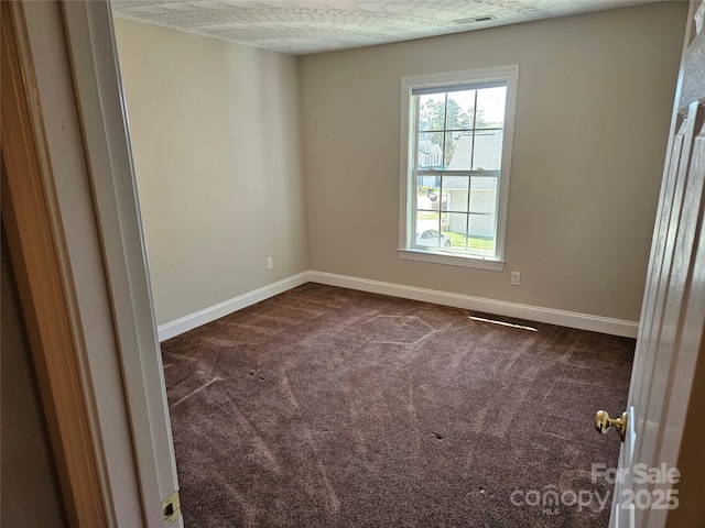spare room with visible vents, baseboards, and dark carpet