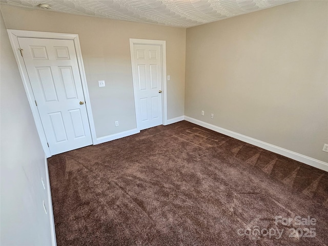 unfurnished bedroom with baseboards and dark colored carpet